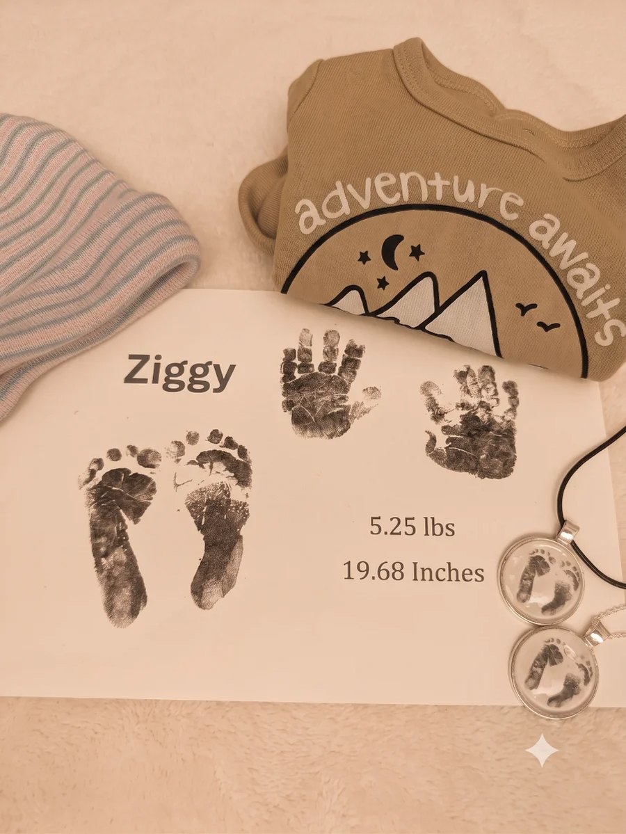 A keepsake print of Ziggy&rsquo;s hands and feet, labelled with his name, 5.25 lbs and 19.68 inches, laid beside a hospital hat, a babygrow and two footprint pendants.